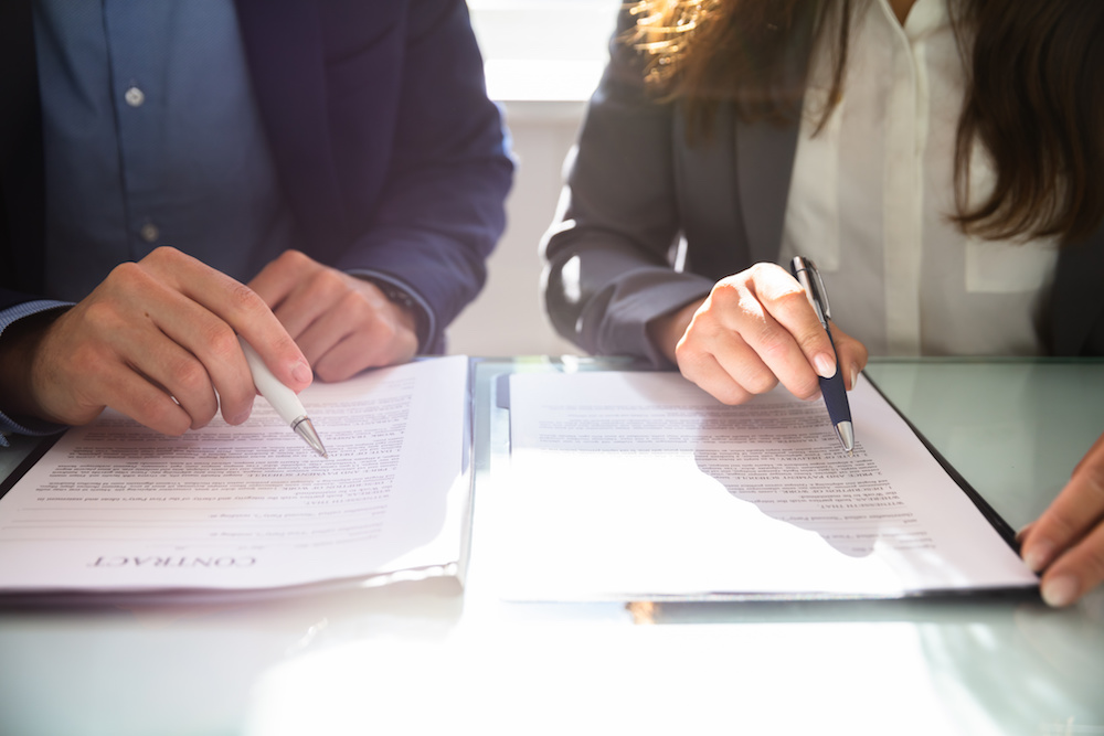 A lawyer and a contract expert witness reviewing a contract that was breached