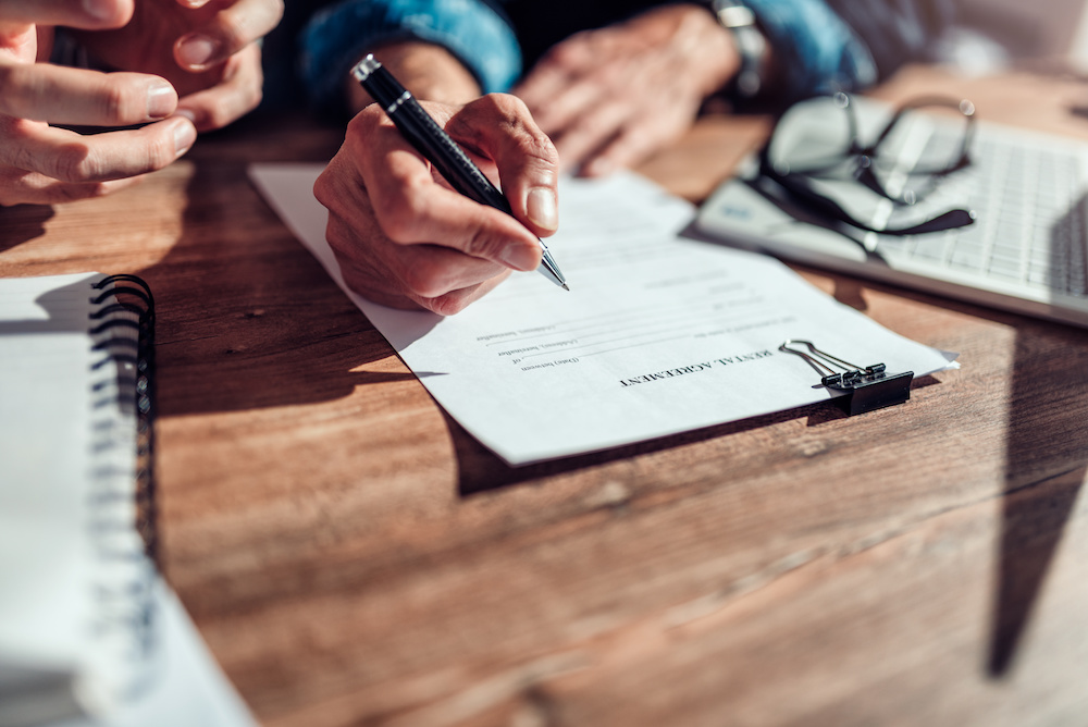 landlord, tenant and expert witness reviewing and signing a lease